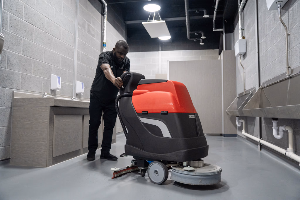 LCS male member of staff using industrial equipment to clean public bathroom floor