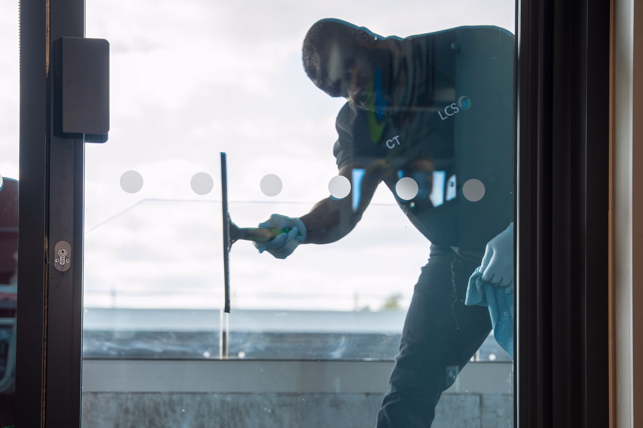 LCS male member of staff cleaning window in a door