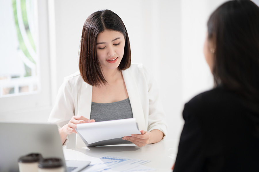 female employee reading paperwork to another female in an office setting