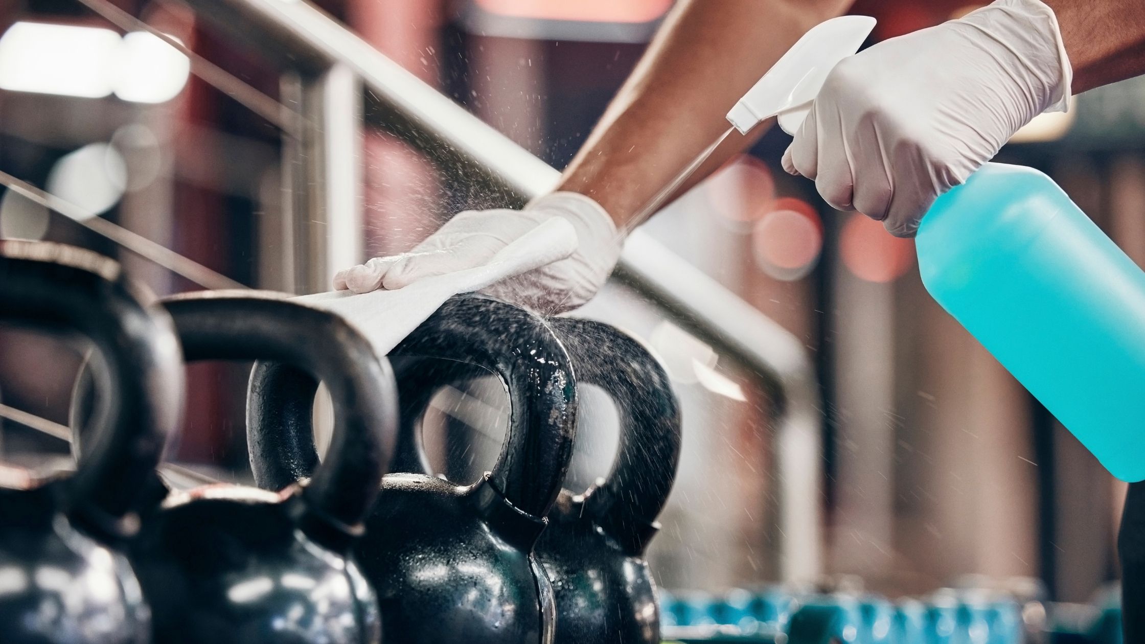 A cleaner cleaning kettlebells in a commercial Gym